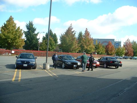 1999 Ford Crown Victoria - Cars and people gathered in a parking lot on a sunny day.
