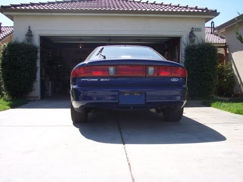1995 Ford Probe - The rear of a blue Ford Probe is visible, with the car parked in front of a suburban garage.