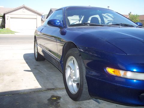 1995 Ford Probe - A blue 1995 Ford Probe is parked in a driveway with a garage in the background.