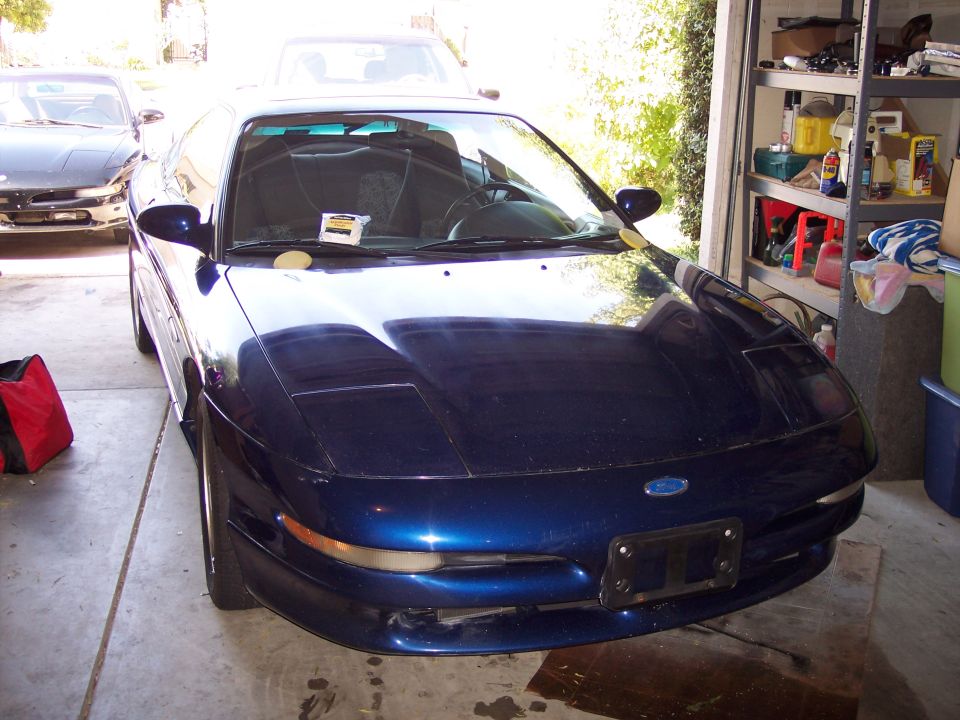 Dark blue Ford Probe coupe parked nose-out in a home garage, front three-quarter view