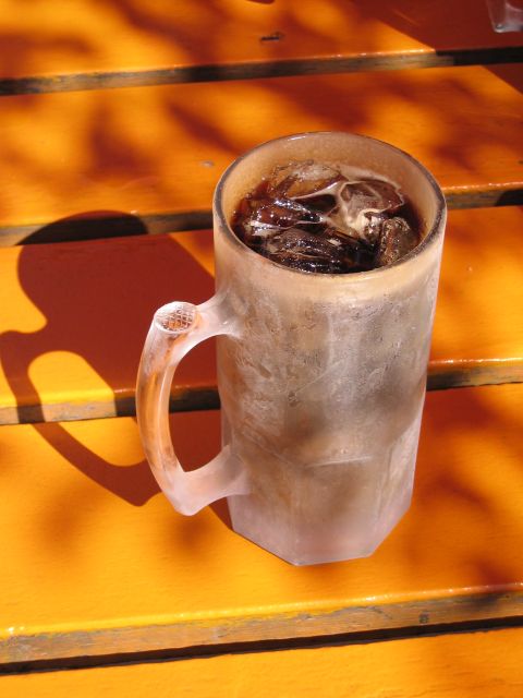 1999 Ford Crown Victoria - A frosty mug filled with root beer and ice is placed on an orange surface with shadows.