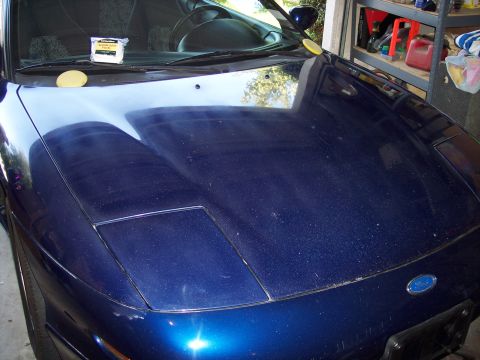 1995 Ford Probe - A blue car with pop-up headlights sits in a garage, with cleaning supplies on the dashboard.