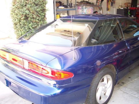 1995 Ford Probe - The rear quarter of a blue 1995 Ford Probe is visible from a three-quarter front angle, parked indoors.