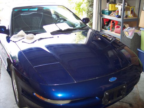 1995 Ford Probe - A blue 1995 Ford Probe is parked in a garage, with papers and cleaning supplies on its hood.