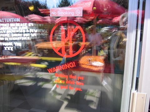1999 Ford Crown Victoria - A restaurant's window displays various signs, including a 'No Smoking' notice and a warning about food and drink quality.