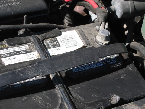 1999 Ford Crown Victoria - Close-up of a car battery, showing various labels and terminals.