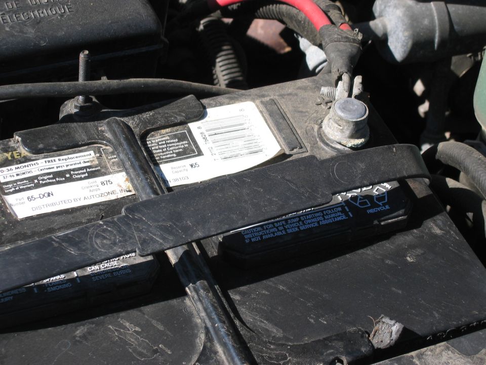 Car battery with labels showing warranty information and caution text