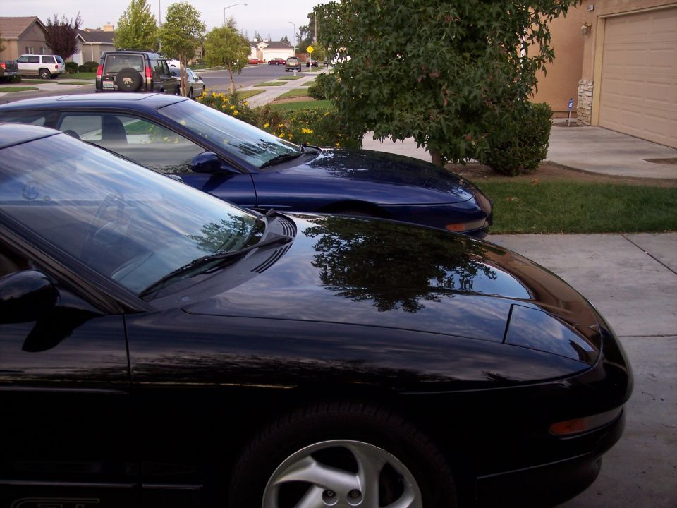 Two blue 1995 Ford Probes parked in a driveway