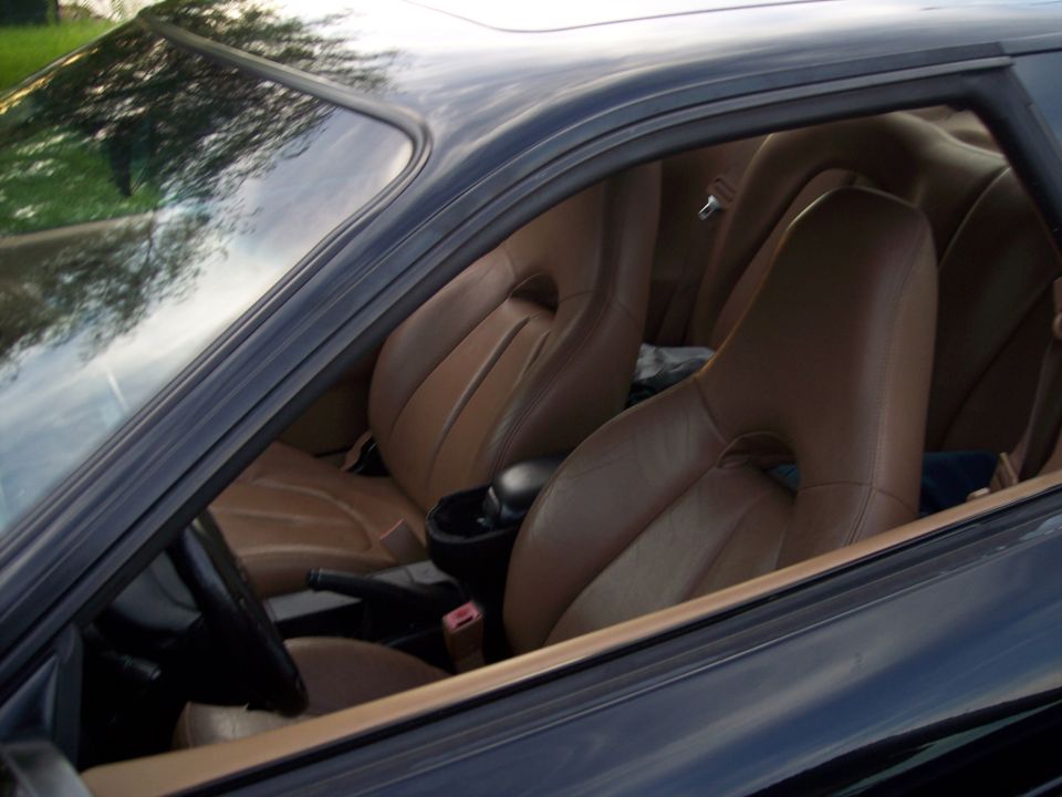 Interior view of a car showing brown leather bucket seats and part of the dashboard