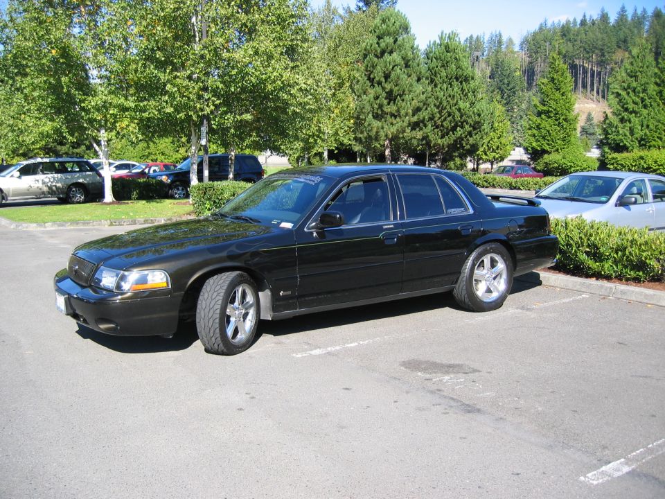 Black sedan parked in a lot, 3/4 front view. Visible text: SUPERMOTORS
