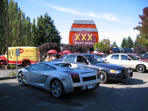 1999 Ford Crown Victoria - A dark blue police car is parked in front of a XXX Root Beer sign.