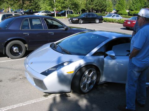 1999 Ford Crown Victoria - A silver sports car is parked next to a dark sedan in a parking lot.