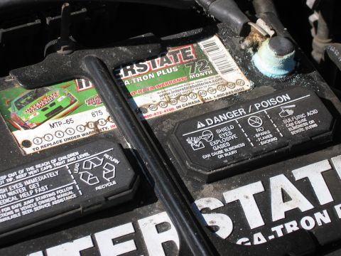 1999 Ford Crown Victoria - A car battery shows Interstate branding, a 72-month warranty, and danger/poison warnings.