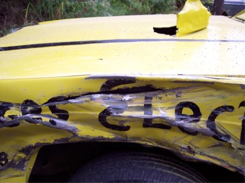 1987 Mercury Grand Marquis - A heavily damaged yellow car with black lettering is shown from the side.