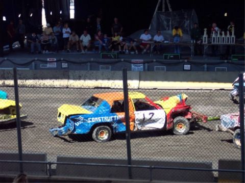 1987 Mercury Grand Marquis - A heavily modified car, painted in multiple bright colors, participates in a demolition derby event.