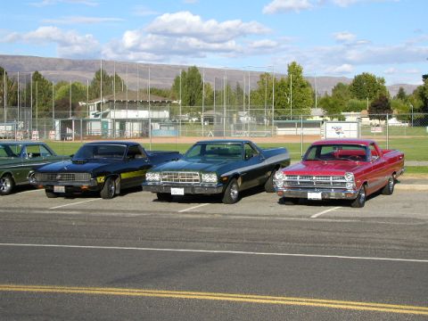 1967 Ford Ranchero - Three Ford Rancheros are parked in a lot with a baseball field in the background.