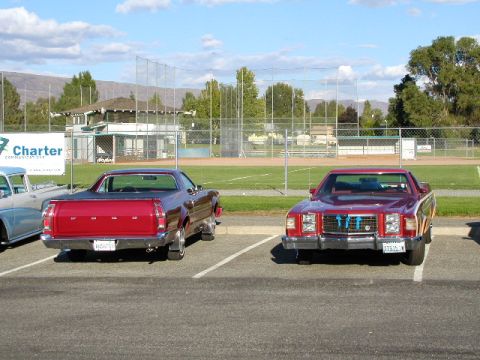 1967 Ford Ranchero - Two Ford Rancheros are parked in a lot with a baseball field behind them.