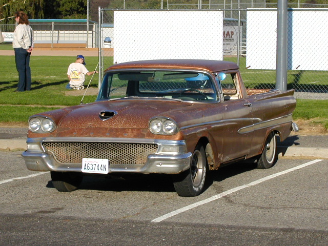 1958 Ford Fairlane pickup with rusty brown paint, parked in a lot