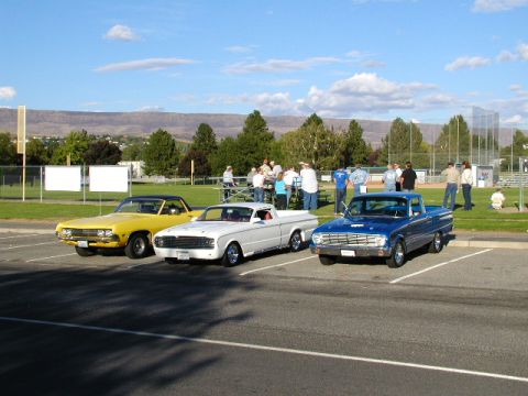 1967 Ford Ranchero - A trio of vintage pickup trucks are on display at an outdoor event, with spectators milling about in the background.