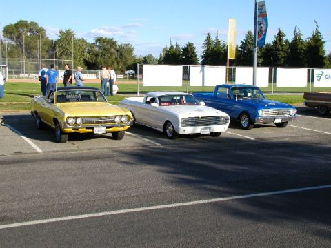 1967 Ford Ranchero - Three classic vehicles are parked in a lot, including a yellow 1967 Ford Ranchero convertible.