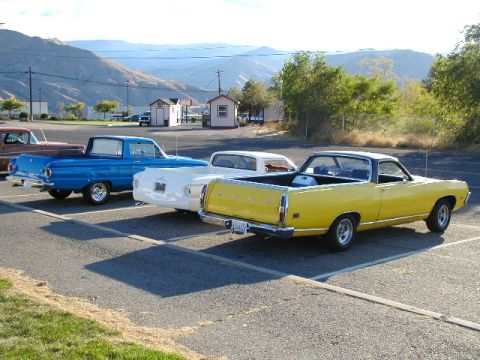 1967 Ford Ranchero - Three classic Ford Rancheros parked in a lot with mountains in the background.