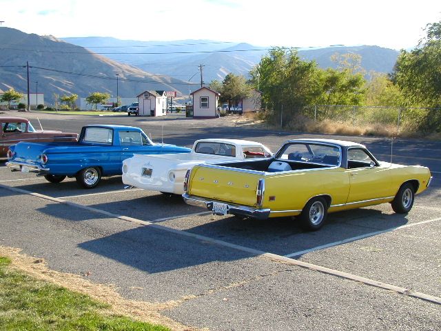 Yellow late-1960s Ford Ranchero seen from rear three-quarter beside two others