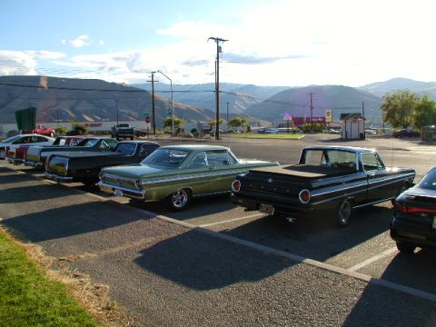 1967 Ford Ranchero - Two classic Ford Rancheros, a coupe and a pickup, are parked side-by-side in a sunny lot with mountains in the background.