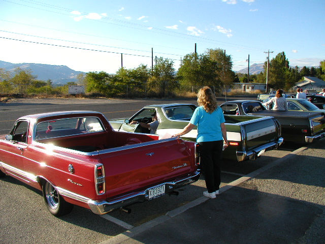 Red Ford Ranchero car-pickup, 3/4 rear view with chrome bed rails at a car show