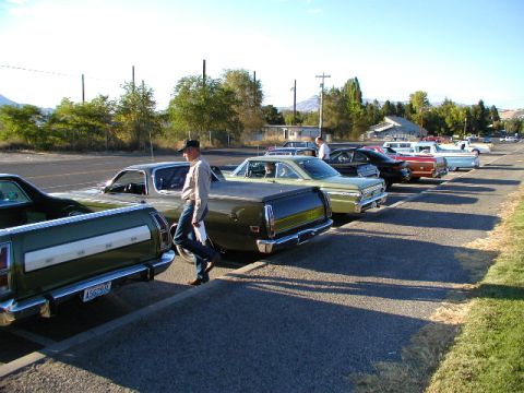 1967 Ford Ranchero - A row of classic vehicles, including a 1967 Ford Ranchero, are parked outdoors.