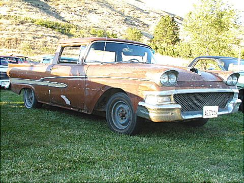1967 Ford Ranchero - A weathered 1957 Ford Ranchero sits on a grassy field, its chrome grille and dual headlights prominent.