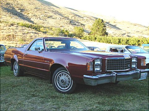 1967 Ford Ranchero - This maroon Ford Ranchero is parked on a grassy field with a hill and trees in the background.