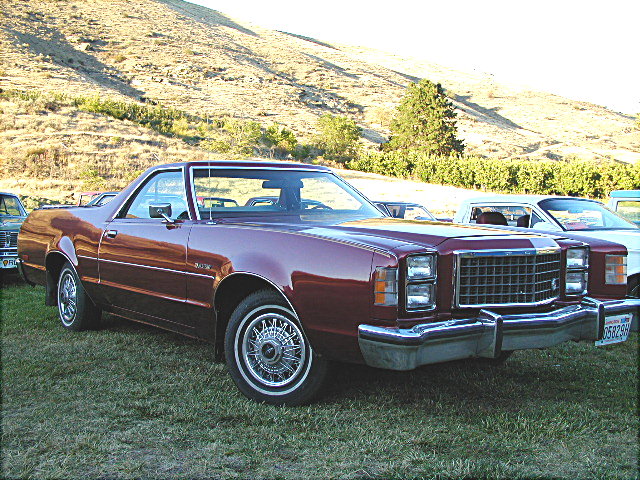 Maroon Ford Ranchero pickup, 3/4 front view on grass with wire wheel covers
