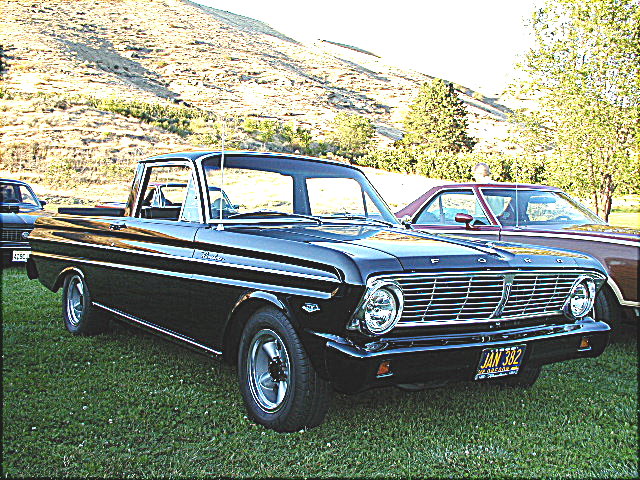 Black 1960s Ford Ranchero coupe utility on grass, front three-quarter view