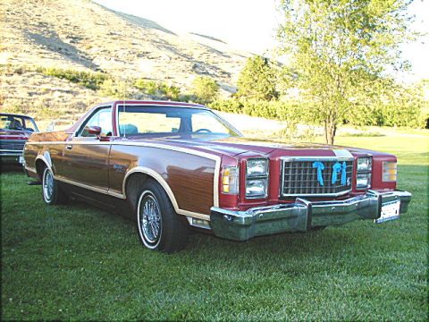 1967 Ford Ranchero - A 1977 Ford Ranchero with wood paneling is parked on a grassy lawn with a hill in the background.