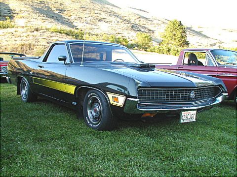 1967 Ford Ranchero - A dark green 1970 Ford Ranchero with a prominent yellow stripe and hood scoop is parked on grass next to a red pickup truck.