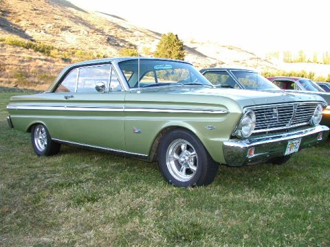 1967 Ford Ranchero - A light green 1964 Ford Falcon coupe is parked on a grassy field with hills in the background.