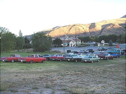 1967 Ford Ranchero - A collection of vintage vehicles are gathered outdoors, with a scenic backdrop of hills and a building.