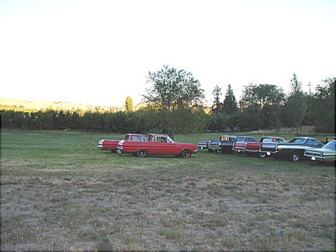 1967 Ford Ranchero - Several vintage vehicles are parked in a field under a bright sky.