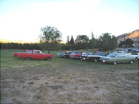 1967 Ford Ranchero - A red 1967 Ford Ranchero is parked in a field with several other classic vehicles.