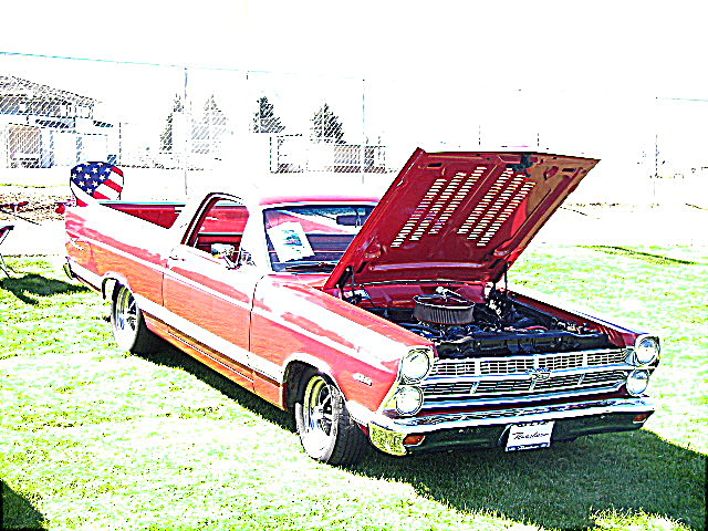 Maroon Ford Ranchero at a car show, hood up, wood-grain trim, flag on antenna