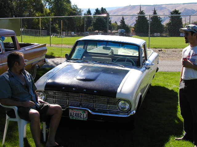 1966 Ford Falcon Ranchero with black hood, parked on grass next to another pickup truck