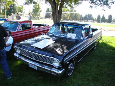 1967 Ford Ranchero - A black 1967 Ford Ranchero is parked next to a red Ranchero at an outdoor event.