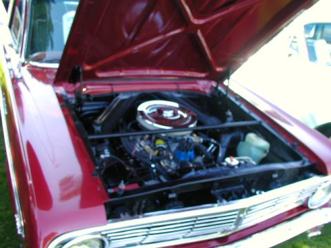 1967 Ford Ranchero - The engine bay of a red 1965 Ford Falcon is visible with the hood raised.