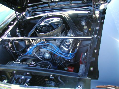1967 Ford Ranchero - The engine bay of a classic car is shown with a chrome air cleaner and blue spark plug wires.
