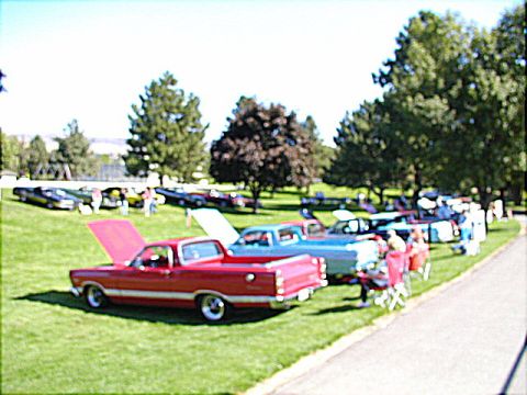 1967 Ford Ranchero - Several classic vehicles, including a red 1967 Ford Ranchero, are parked on a grassy field at an outdoor event.