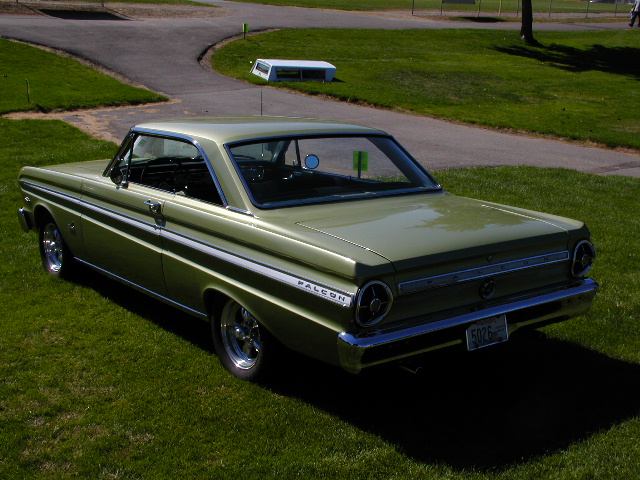 Gold 1960s Ford Falcon two-door hardtop rear three-quarter view on grass