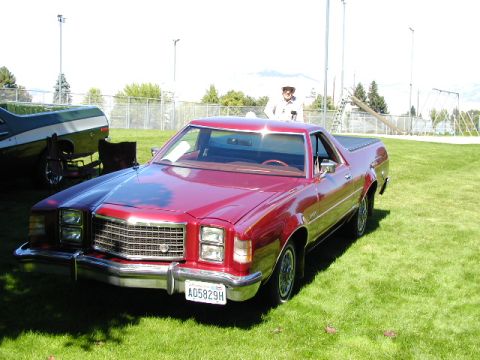 1967 Ford Ranchero - A red Ford Ranchero is parked on a grassy field, with another vehicle partially visible in the background.