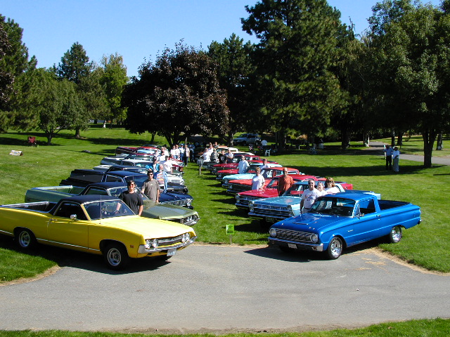 Two rows of Ford Rancheros parked on a park lawn at a club meet, yellow and blue in front