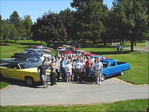 1967 Ford Ranchero - A gathering of classic car enthusiasts poses with their vehicles, including a yellow 1967 Ford Ranchero.