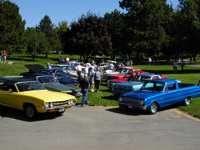 Yellow 1967 Ford Ranchero and blue 1960s Ford Ranchero parked at outdoor car show with other vehicles